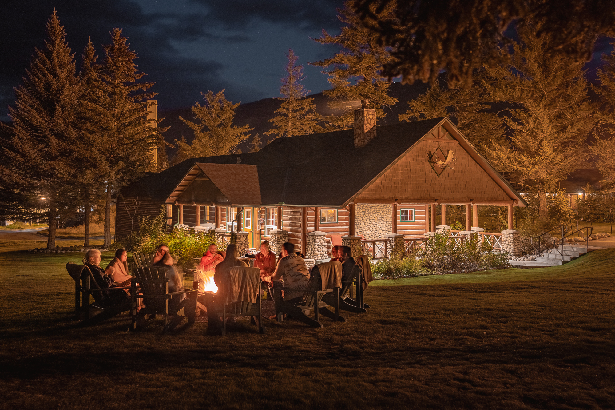 A group gathered together around a fire outside a cabin